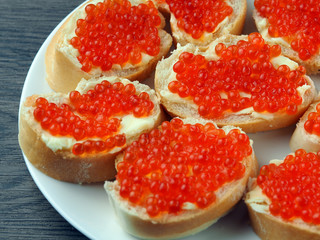Red caviar on sandwiches on a wooden table