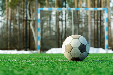 Old football ball left on soccer field. White soccer ball with no branding. Close up.