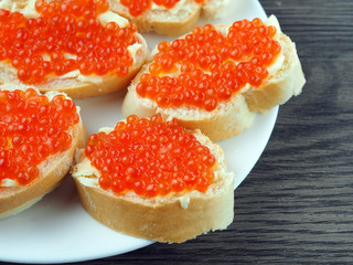 Red caviar on sandwiches on a wooden table