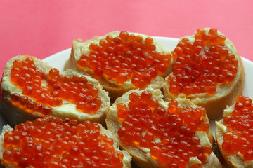 Red caviar on sandwiches in a plate on a coral background