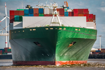 Frontal-Aufnahme eines grünen Containerschiffes