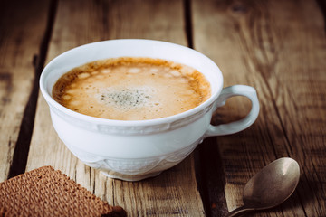 coffee with froth in vintage cup on wooden background