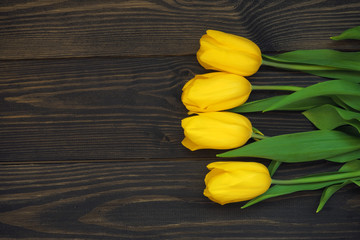 Yellow tulips lie on a dark wooden table.