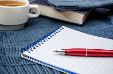 notebook, pen, book and a cup of tea on blue