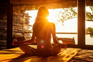 Fotobehang woman sun rays in the form of chakras in tropical yoga studio a view outside to the hills while sunset.girl in eco hotel panoramic windows enjoying solitude with nature Kerala India wildernest resort © yurakrasil