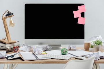 modern workplace with computer, stationery and crumpled papers at wooden desk isolated on grey