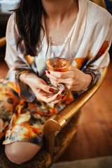 Unrecognizable woman in bathrobe holding glass of wine.