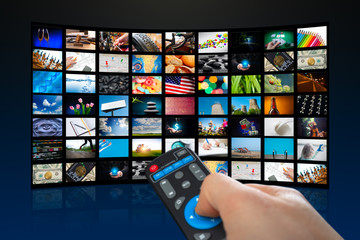 TV screen with lot of pictures and hands of man with remote control on blue background