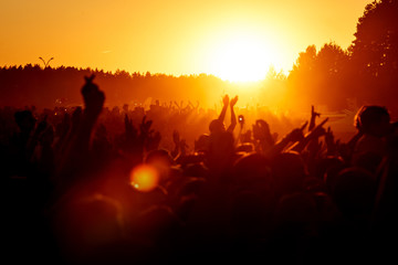 Crowd dancing on the summer party. Low sun orange light.