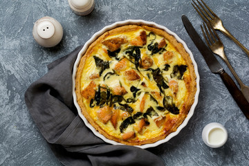Homemade quiche tart with red fish and spinach on light wooden background. Vintage style. Top view.