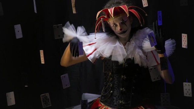 A joker with a hat and black and white makeup is performing a mime show