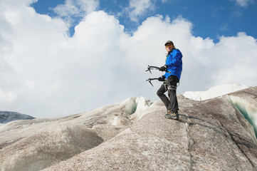 Traveler in a cap and sunglasses standing with ice ax in the snowy mountains on the glacier. Traveler in a natural environment