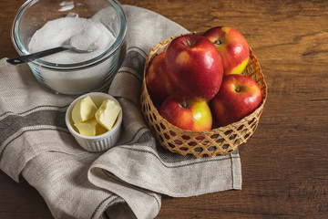 Red apple in the basket with sugar, butter, and salt. Ingredients for making apple pie or tarte tatin.