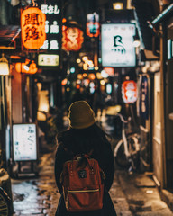 Naklejka premium Woman tourist wearing beanie walking the colourful streets of Osaka, Japan.