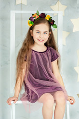 Portrait of a beautiful blue-eyed girl, little sitting on a chair. Spring break, Mother's Day, Women's Day.