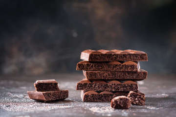 Stack of bitter porous airy chocolate on dark old background. Selective focus.