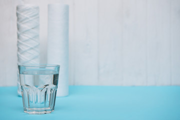 Water filters. Carbon cartridges and a glass on a white blue background. Household filtration...