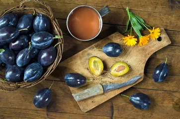 Foto op Plexiglas Plums in a basket and plum juice on a wooden table © eladstudio