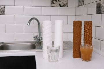 Water filter cartridge used and a glass of rusty water brown coloring and new filter and a glass of...