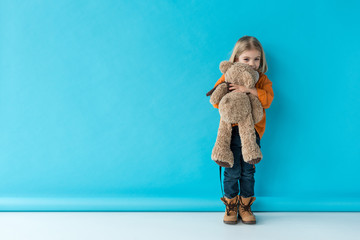 cute and adorable kid holding teddy bear on blue background