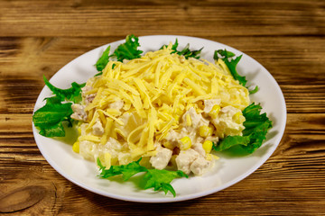 Festive salad with chicken breast, sweet corn, canned pineapple, cheese and mayonnaise on wooden table