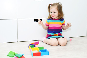 Little girl playing with educational toy at home on the floor