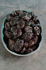 Rustic plate with tasty smoked dried plums on a dark gray background