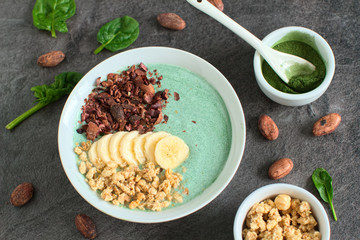 Healthy smoothie made from green raw ingredients on a dark gray background