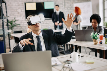 Businessman having fun while using virtual reality simulator in the office.