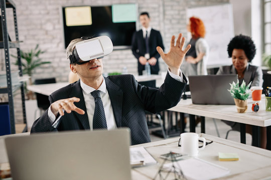 Businessman having fun while using virtual reality simulator in the office.