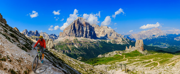 View of cyclist riding mountain bike on single trail in Dolomites, Cinque Torri, South Tirol, Italy