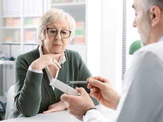 Professional doctor giving a prescription medicine to a senior patient