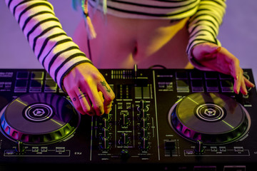 Asian girl DJ is playing a turntable in night party is colorful.