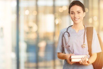 Attractive young female doctor student on background