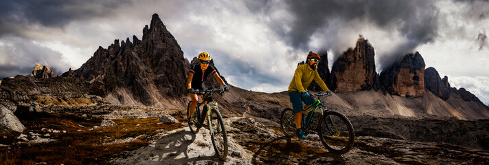 Single mountain bike rider on electric bike, e-mountainbike rides up mountain trail. Man riding on bike in Dolomites mountains landscape. Cycling e-mtb enduro trail track. Outdoor sport activity.