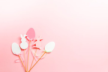 Easter composition with traditional decor. Decorative eggs and rabbits on wooden sticks on pink soft background.