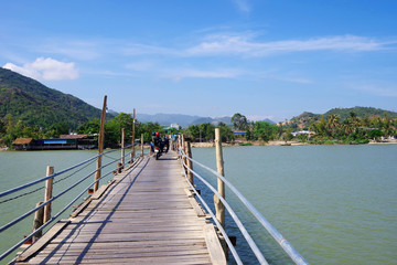 Fototapeta na wymiar wooden bridge across the river with motorbikes traveling along it, Vietnam