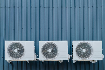 Three air conditioner outdoor units on a blue wall. Copy-space.
