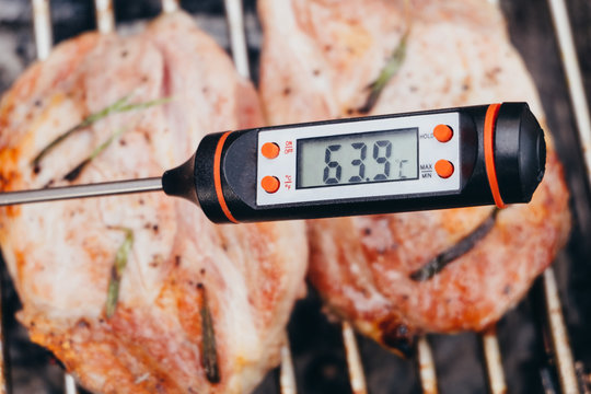 Cooking thermometer against pork steak