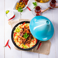 Tajin with couscous, vegetables and meat on white background