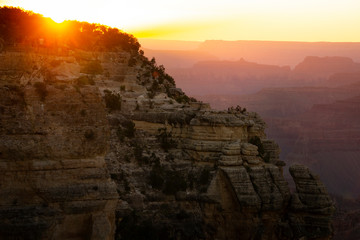 A colorful sunset at Grand Canyon National Park with and orange and gold layered sky.

