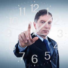 Businessman in a suit shows fingers on the clock. Clock on wall. Concept price time.