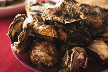 Steamed oysters in a plate on red table cloth. Selected focus. Copy space. Toned picture.
