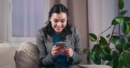 Happily surprised businesswoman using mobile phone on sofa at home