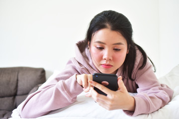 Women using mobile smartphone is ion bedroom