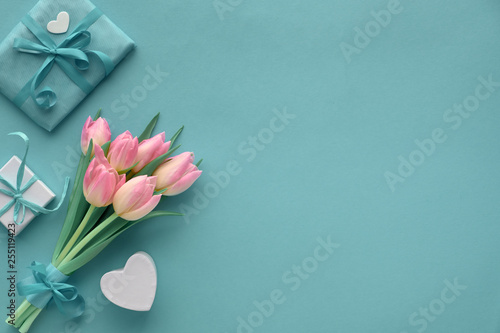 Springtime turquoise paper background with pink tulips and wrapped gifts, copy-space