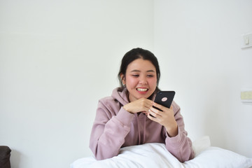 Fototapeta premium Women using mobile smartphone is ion bedroom