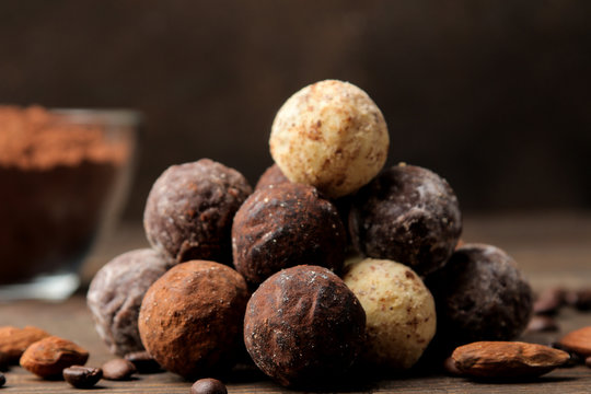 assorted chocolates. candy balls of different types of chocolate on a brown wooden table. cinnamon and almonds