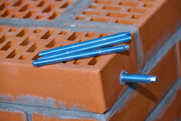  set of parts for mounting anchors in hollow brick and concrete lie on the surface of the brickwork in any order. Threaded studs.