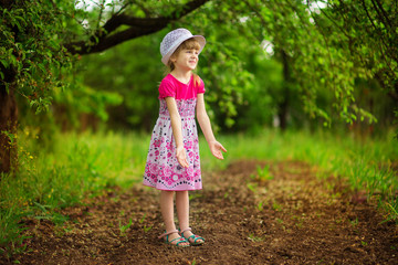 Happy little girl in bright dress walk in garden